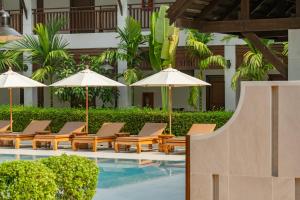 a group of lounge chairs and umbrellas next to a swimming pool at Rimping Village in Chiang Mai