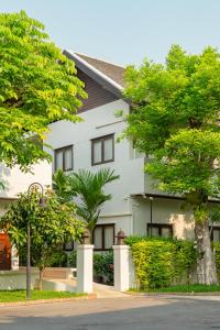 a white house with trees in front of it at Rimping Village in Chiang Mai