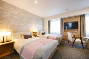a hotel room with two beds and a television at JR-East Hotel Mets Kitakami in Kitakami