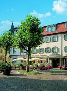 een groot gebouw met een boom ervoor bij Hotel Goldener Karpfen OHG in Fulda