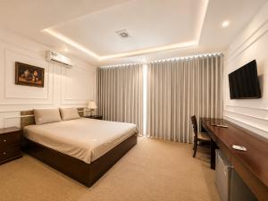 a bedroom with a bed and a desk and a television at X-Stay Cloud in Hai Phong