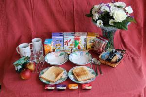 een tafel met sandwiches en ontbijtproducten en een vaas met bloemen bij The Stables B&B @ Pear Tree Cottage in Winslow