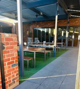 eine Terrasse mit Tischen und Bänken in einem Backsteingebäude in der Unterkunft Echuca Hotel in Echuca