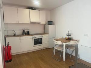 a kitchen with white cabinets and a table with chairs at A Casa da Praça - The Square House in Miranda do Corvo