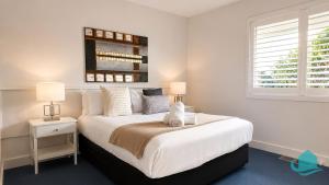 a white bedroom with a large bed and a window at Plover Executive Deluxe Villa 25 in Cams Wharf