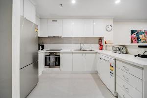 a white kitchen with white cabinets and a sink at Central 2-bed Apartment with Gym and Spa in Canberra