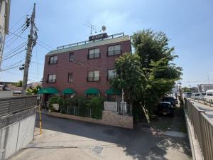 a red brick building with a restaurant on a street at ビジネスイン拝島 in Akishima