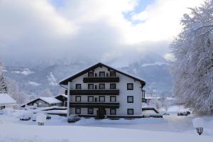 ein großes weißes Haus mit Schnee auf dem Boden in der Unterkunft Hotel Köppeleck in Schönau am Königssee