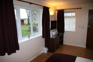 a living room with two windows and a dresser at The Stables B&B @ Pear Tree Cottage in Winslow