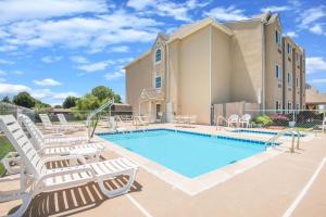a swimming pool with lounge chairs and a building at Microtel Inn & Suites Claremore Route 66 in Claremore