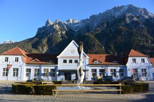a building with a statue in front of it with mountains at Ferienhaus Bichler in Mittenwald