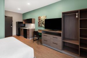 a hotel room with a bed and a flat screen tv at ECHO Suites Extended Stay by Wyndham Houston Katy West in Katy
