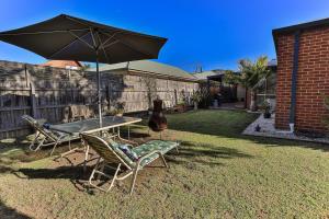 a patio with a table and chairs and an umbrella at Phillip Island Dream Getaway in Ventnor