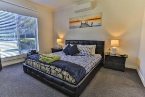 a bedroom with a black bed with two lamps and a window at Phillip Island Dream Getaway in Ventnor