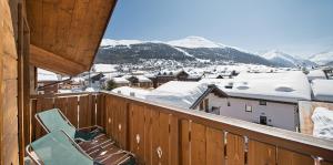 uma varanda com uma cadeira e montanhas cobertas de neve em Hotel Cervo em Livigno