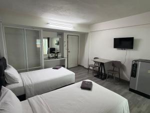 a hotel room with two beds and a table at The Bless Residence in Hat Yai