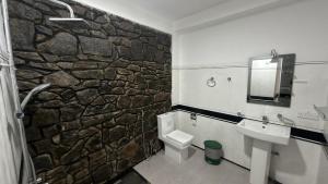 a bathroom with a stone wall and a toilet and sink at Forest Rawana homestay Ella in Ella +215 photos