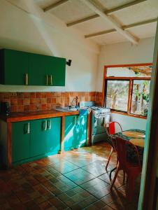 a kitchen with green cabinets and a table and a table and chairs at Beautiful cabin on Easter Island in Hanga Roa
