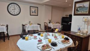 a dining room with a table with food and a clock at Hospedaje Boutique Weber's in Gijón