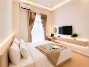 a white bedroom with a large bed and a flat screen tv at Amory Airport Hotel in Ho Chi Minh City