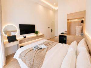 a white bedroom with a large bed and a flat screen tv at Amory Airport Hotel in Ho Chi Minh City +38 photos