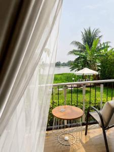 ein Balkon mit Tisch, Stuhl und Fenster in der Unterkunft White Wall Riverfront Hotel in Kamphaeng Phet