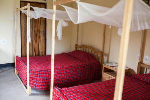 a bedroom with two beds with red plaid sheets at The Elephant Home in Katunguru