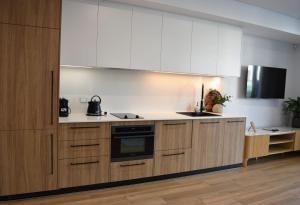 a kitchen with wooden cabinets and a tv on the wall at Kove Apartment - G05 in Kiama