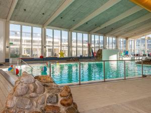 a large swimming pool in a building with windows at Søndervig Holiday Center in Ringkøbing