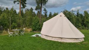 a tent in a field with a table and chairs at Glampingtält in Österbybruk