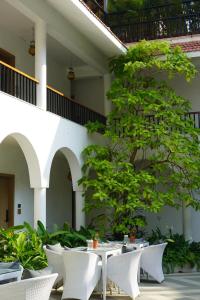 a patio with white tables and chairs and a tree at Bougainvillea in Nagaon