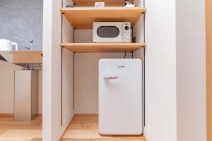 a refrigerator in a kitchen with a microwave on a shelf at Hotel Arina HakataTaihaku in Fukuoka