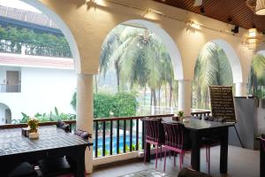 a restaurant with two tables and a balcony with palm trees at Bougainvillea in Nagaon