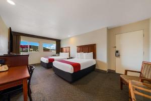 a hotel room with two beds and a desk at Rodeway Inn South San Francisco Airport in South San Francisco