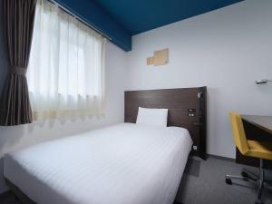 a bedroom with a white bed and a desk and a window at Comfort Hotel Wakayama in Wakayama