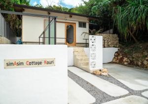 a dog laying on the ground in front of a house at simAsim Cottage Kouri in Nakijin