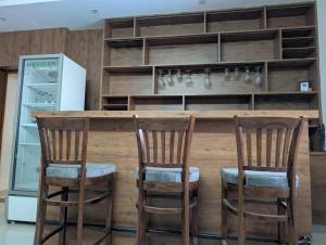 a kitchen with a bar with three wooden chairs at Karmawas House in Jodhpur