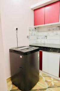 a black refrigerator in a kitchen with red cabinets at Varkala Escape Resort in Varkala