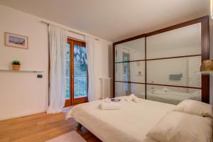 a bedroom with a large white bed and a large window at Lenni Apart. Swimming Pool and lake + WIFI - Happy Rentals in Leggiuno