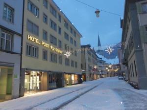 a snowy street with a hotel root x star sign at Central Hotel Post in Chur