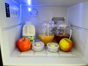 an open refrigerator with apples and juice and milk at Sunset House in Penrith