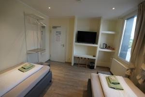 a hotel room with two beds and a tv at Pension Dortmund Messe in Dortmund