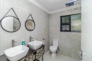 a bathroom with a sink and a toilet and a mirror at Urban Escapes - LINDEN COTTAGE in Johannesburg +11 photos