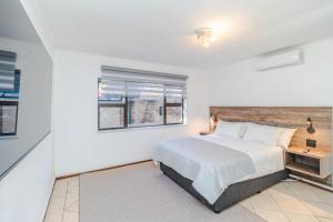 a white bedroom with a bed and a window at Urban Escapes - LINDEN COTTAGE in Johannesburg