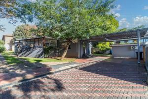 a brick road in front of a building with a tree at Urban Escapes - LINDEN COTTAGE in Johannesburg