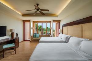 a bedroom with two beds and a ceiling fan at Centara Grand Beach Resort Phuket in Karon Beach