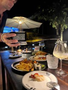 a man is holding a bottle of wine and plates of food at Bearwolf Koh Kood in Ko Kood