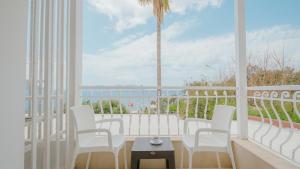 a balcony with white chairs and a table and a palm tree at Hotel No37 in Kaş +1 photo