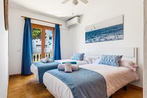 two beds in a room with blue curtains at Apartamentos Mar Blanca by Mauter Villas in Cala Blanca +69 photos