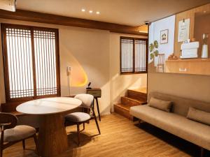 a waiting room with a table and chairs and a stairway at Moonraejung Hostel in Seoul